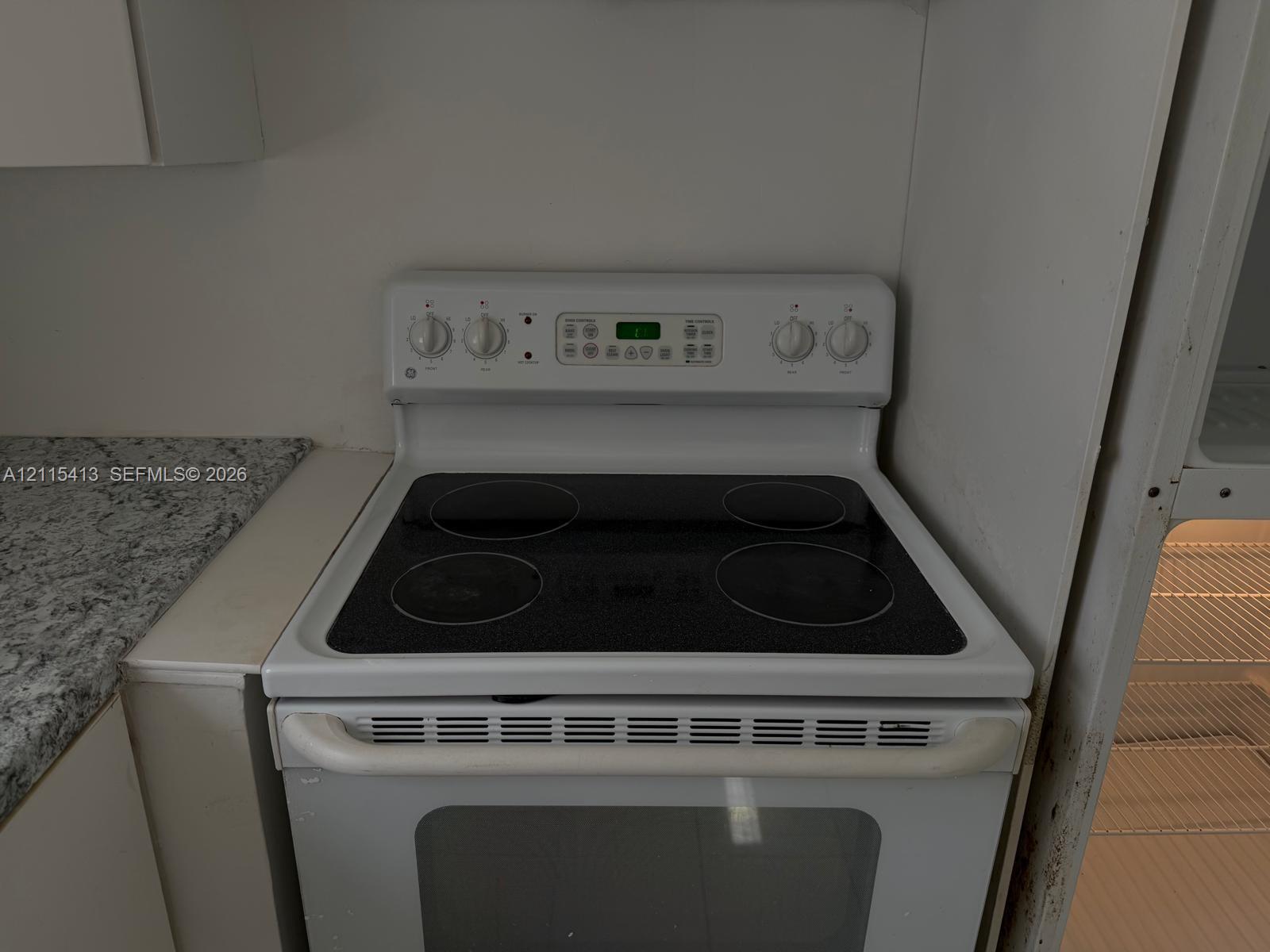 White electric range with a glass cooktop, digital control panel, and solid-surface countertop