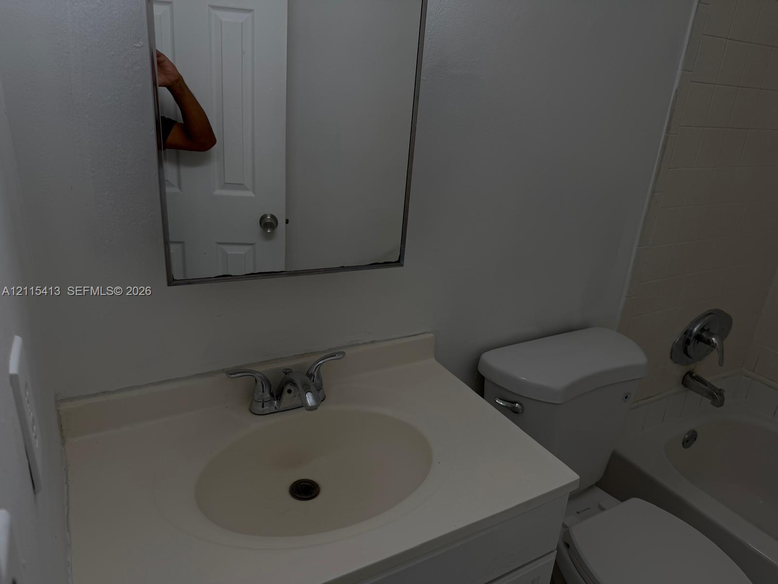 Bathroom vanity featuring an integrated oval sink basin, chrome-finish dual-handle faucet, frameless wall-mounted mirror, and combination shower and tub enclosure with chrome fixtures