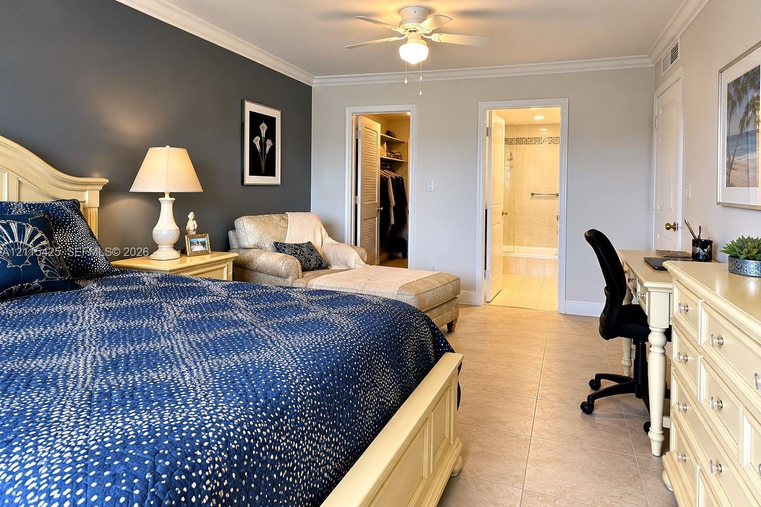 Room featuring an accent wall, tile flooring, crown molding, a ceiling fan, and a walk-in closet