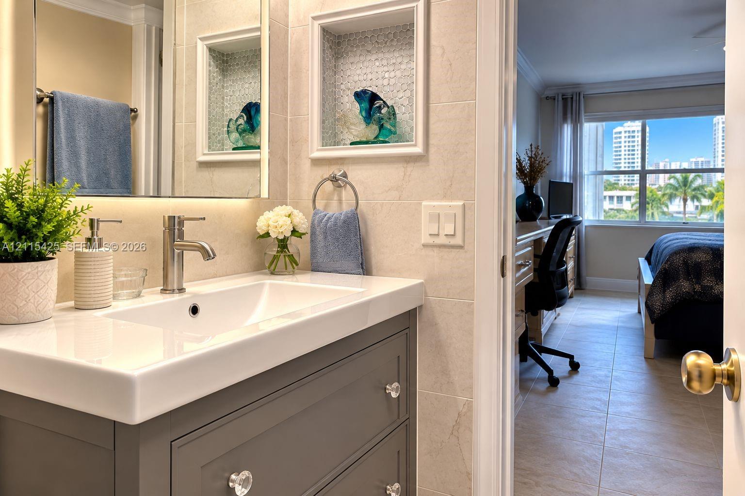 Vanity featuring a rectangular basin, quartz countertop, and grey cabinetry with crystal-style hardware, accompanied by a recessed wall niche with tiled backsplash