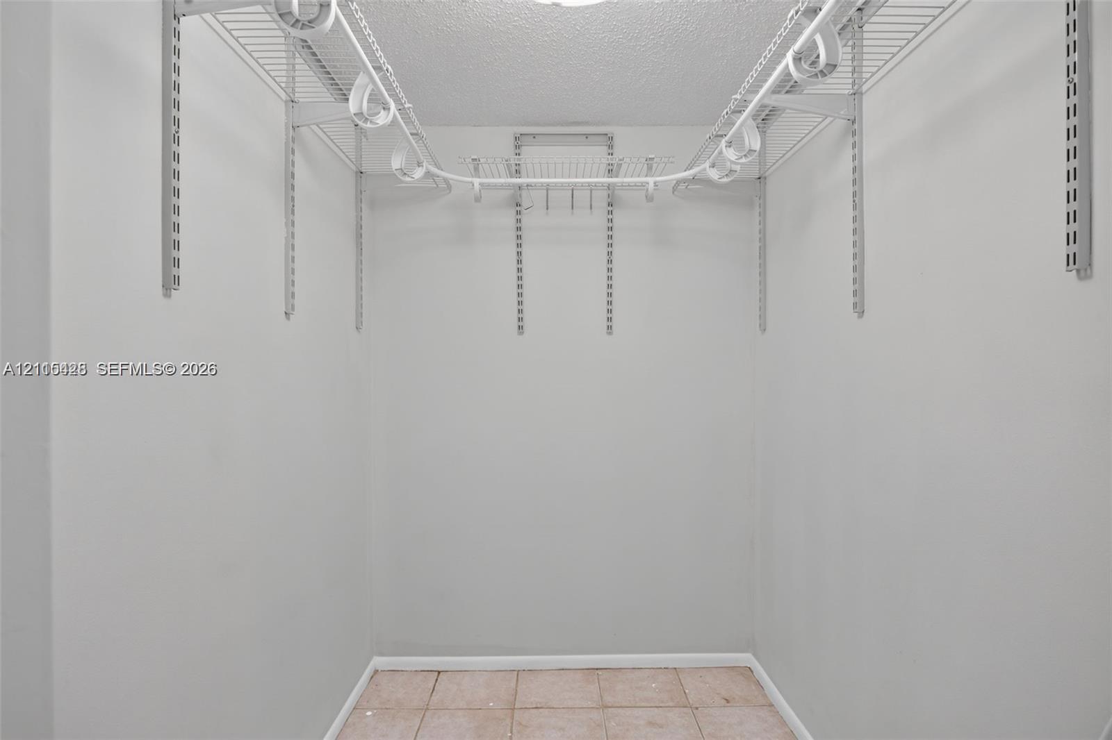 Storage space featuring adjustable wall-mounted metal shelving, white support tracks, and tile flooring