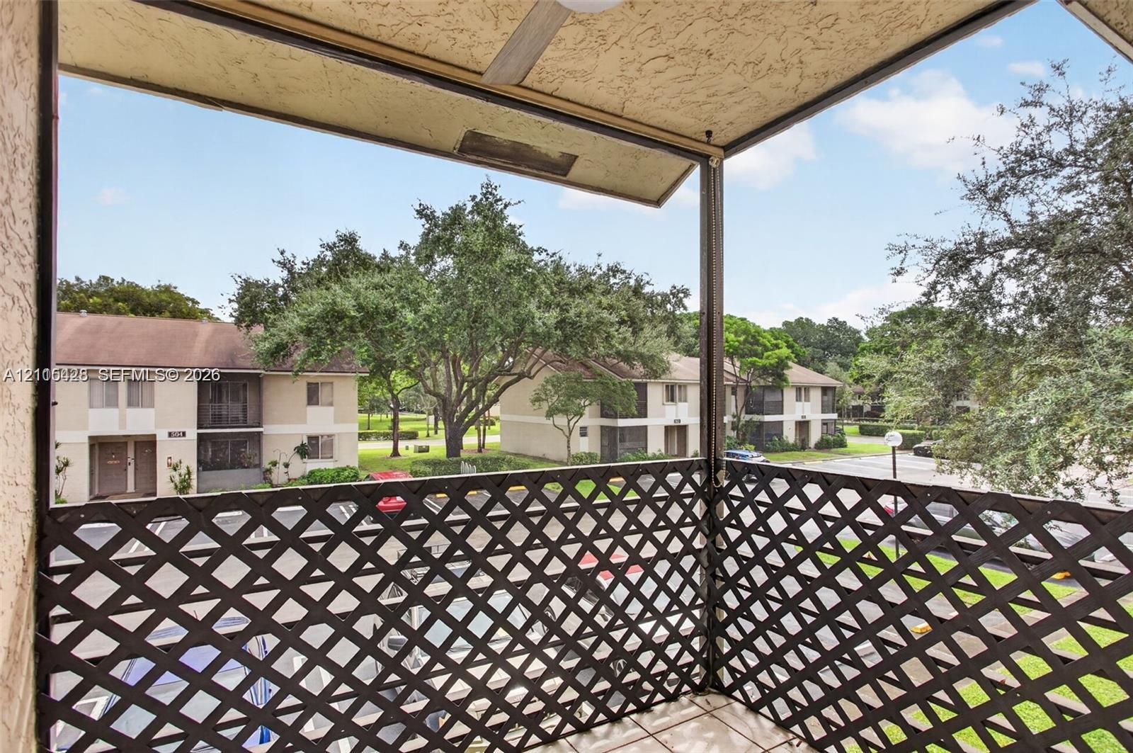 Covered balcony featuring a diamond-patterned lattice railing and a mounted ceiling fan
