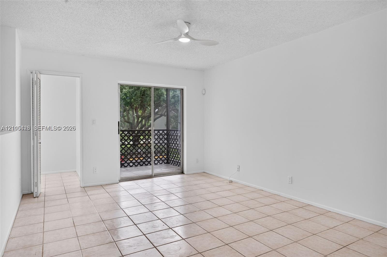 Interior space featuring neutral ceramic tile flooring, a minimalist ceiling fan, and sliding glass doors opening to a screened balcony