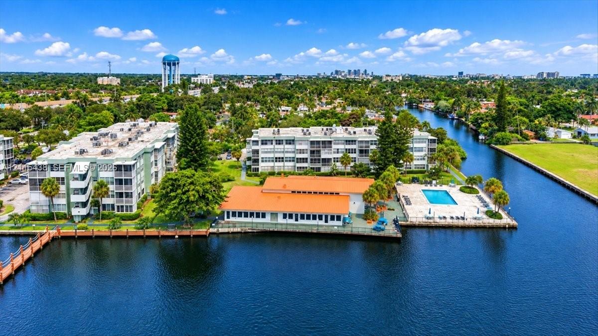 Waterfront complex featuring a swimming pool, concrete dock, and multi-story residential buildings with clay tile roofing
