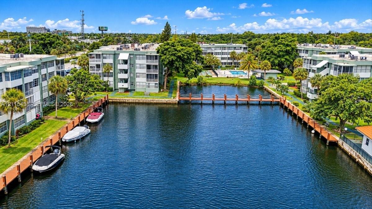 Waterfront property featuring a private canal, multi-slip wooden bulkhead, pedestrian footbridge, and landscaped green space
