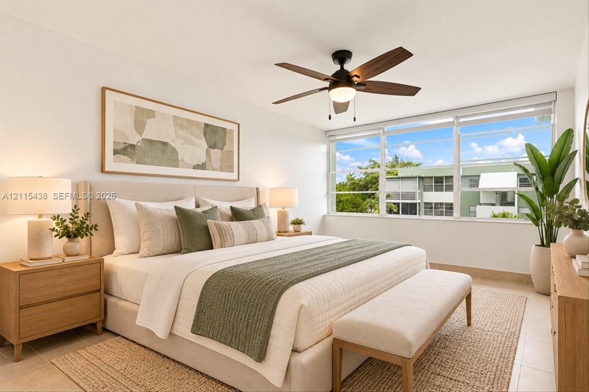Neutral-toned interior featuring large-format tile flooring, oversized horizontal window with exterior scenery, and a central ceiling fan with integrated light fixture Neutral-toned interior featuring large-format tile flooring, oversized horizontal window with exterior scenery, and a central ceiling fan with integrated light fixture