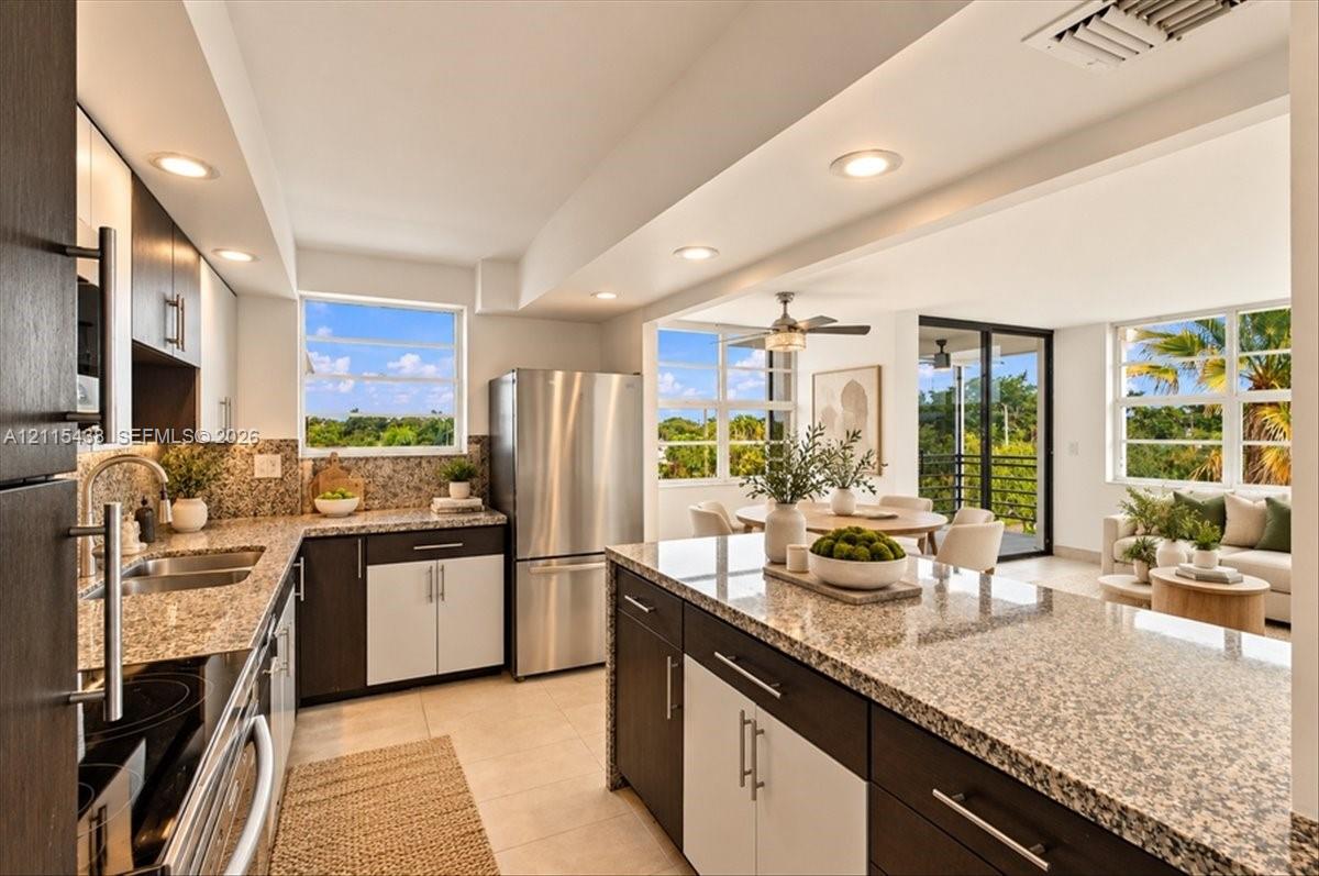 Kitchen featuring two-tone cabinetry, stone countertops, stainless steel appliances, a center island with breakfast bar seating, and recessed lighting