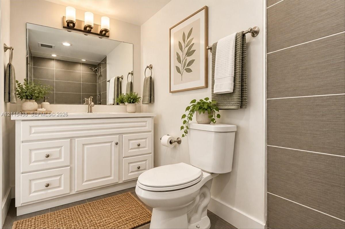White shaker-style vanity with storage drawers, expansive wall-mounted mirror, three-bulb vanity lighting, and oversized horizontal shower tiling