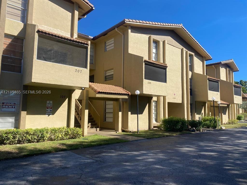 Multi-story exterior featuring textured stucco facade, tile roof accents, screened balconies, and built-in exterior lighting Multi-story exterior featuring textured stucco facade, tile roof accents, screened balconies, and built-in exterior lighting