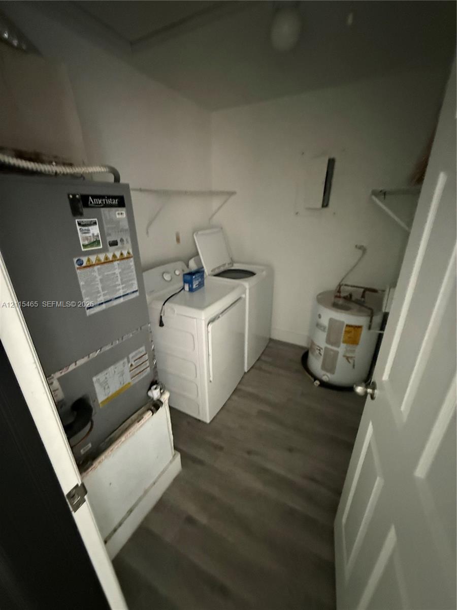 Utility area featuring wood-finish flooring, white wire shelving, an integrated HVAC system, and a dedicated water heater