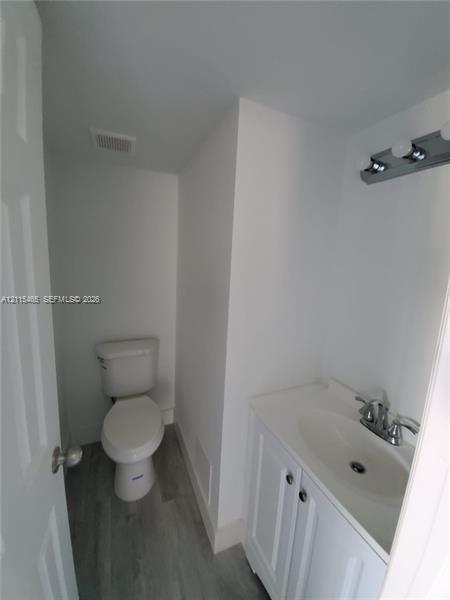 White vanity cabinet with an integrated basin, chrome-finish dual-handle faucet, neutral wood-finish flooring, and a multi-bulb light fixture White vanity cabinet with an integrated basin, chrome-finish dual-handle faucet, neutral wood-finish flooring, and a multi-bulb light fixture