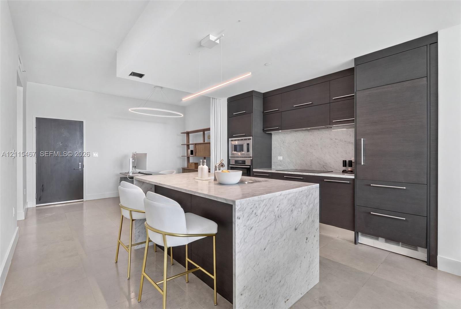 Kitchen featuring flat-panel cabinetry, stone countertops with waterfall edge island, built-in panel-ready refrigerator, and linear pendant lighting