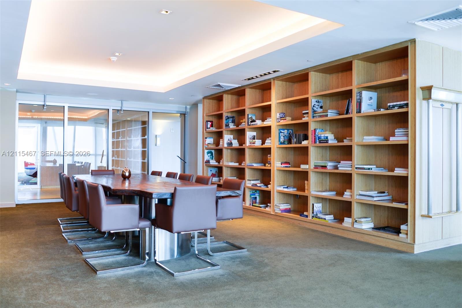 Floor-to-ceiling built-in wood shelving, coffered ceiling with recessed lighting, and expansive glass paneled partitions