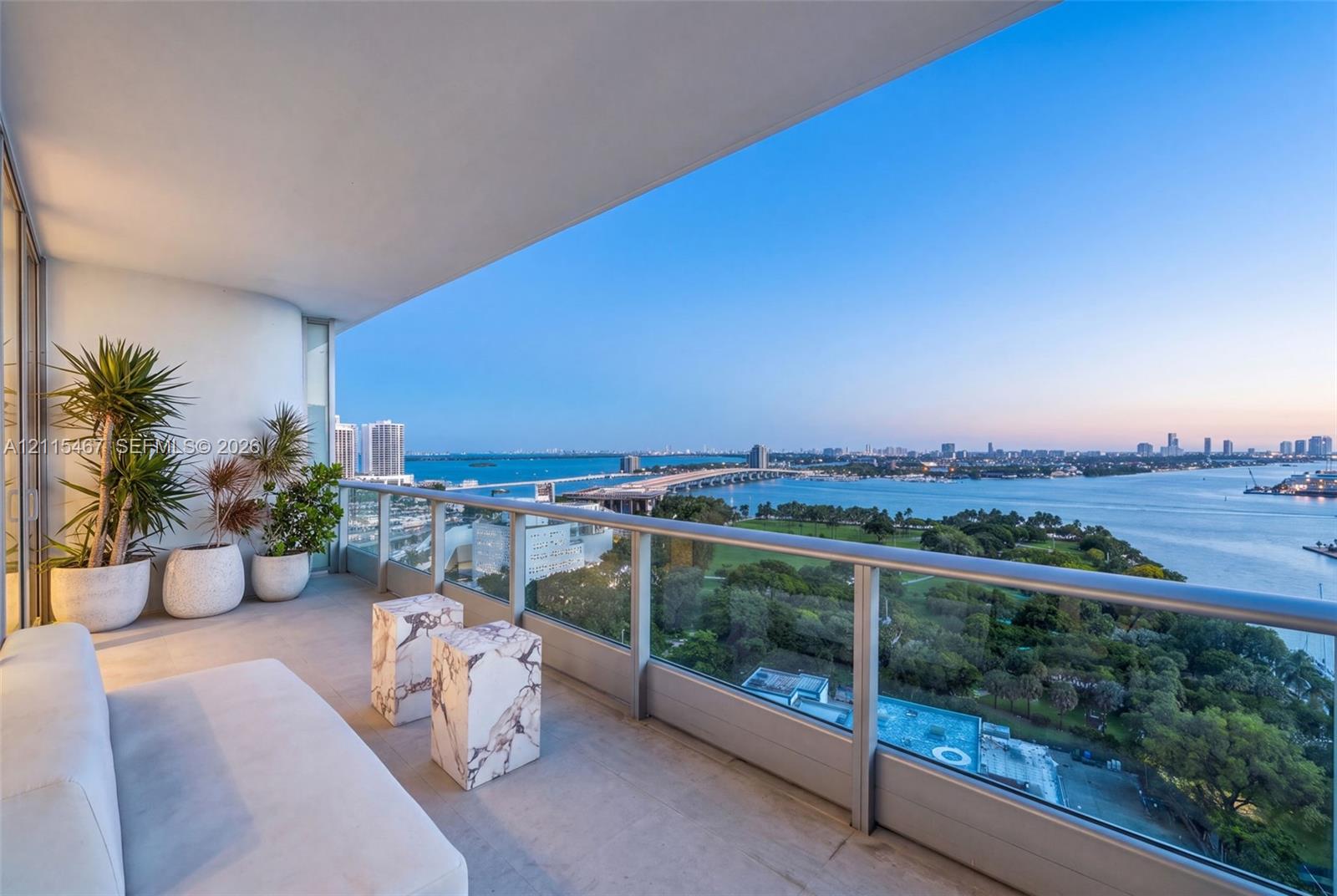 Covered balcony with concrete flooring, glass railing, and expansive panoramic waterfront scenery