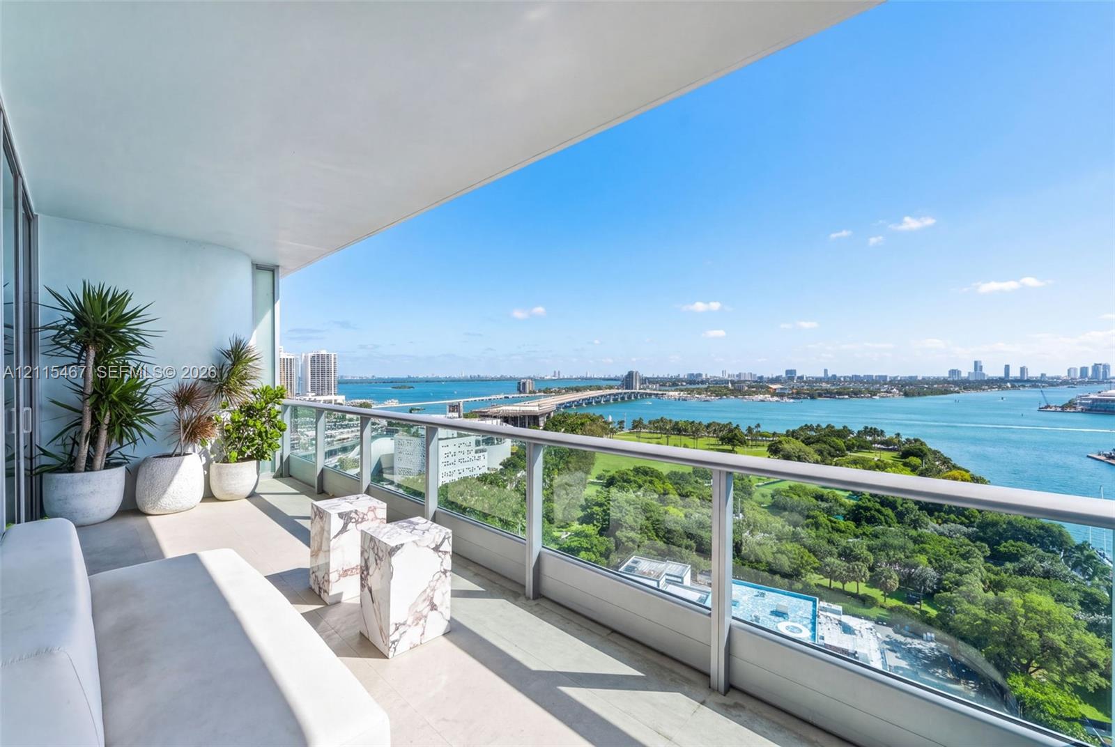 Covered balcony featuring concrete flooring and a glass-paneled railing system with a metal frame