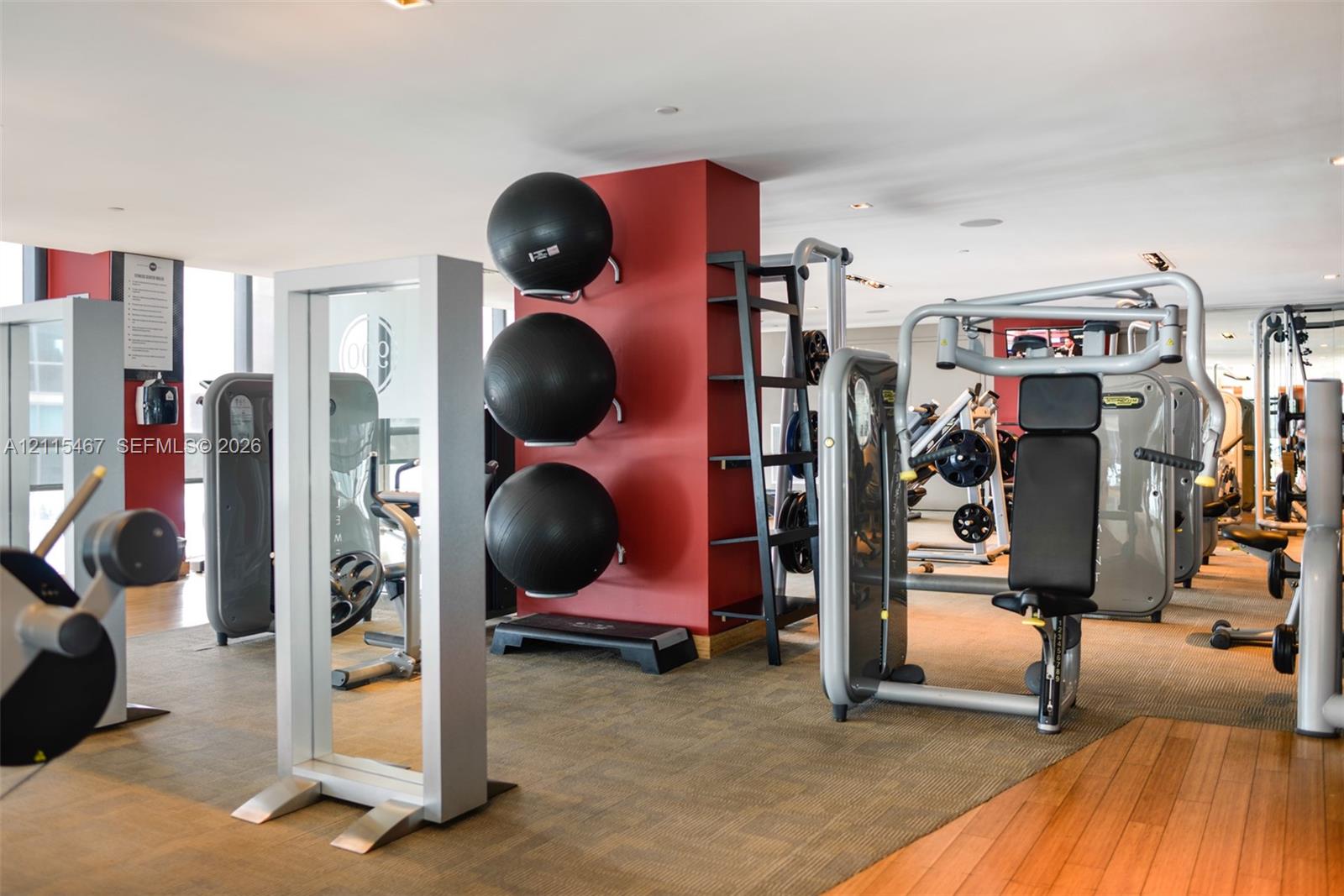 Fitness area featuring wood-finish flooring, recessed lighting, and wall-mounted storage racks