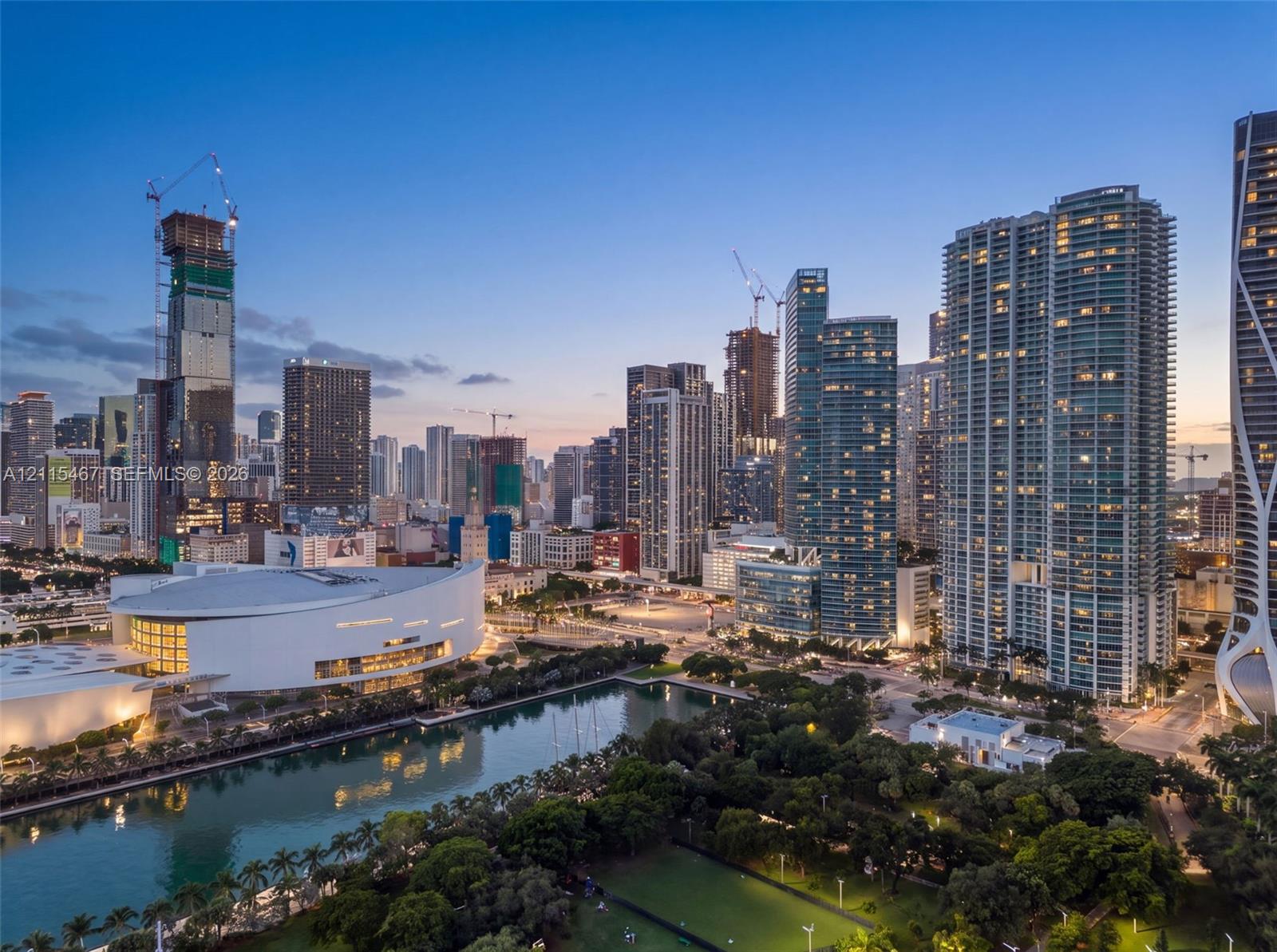 Panoramic cityscape featuring high-rise architecture, a multi-purpose arena, waterfront access, and mature canopy greenery