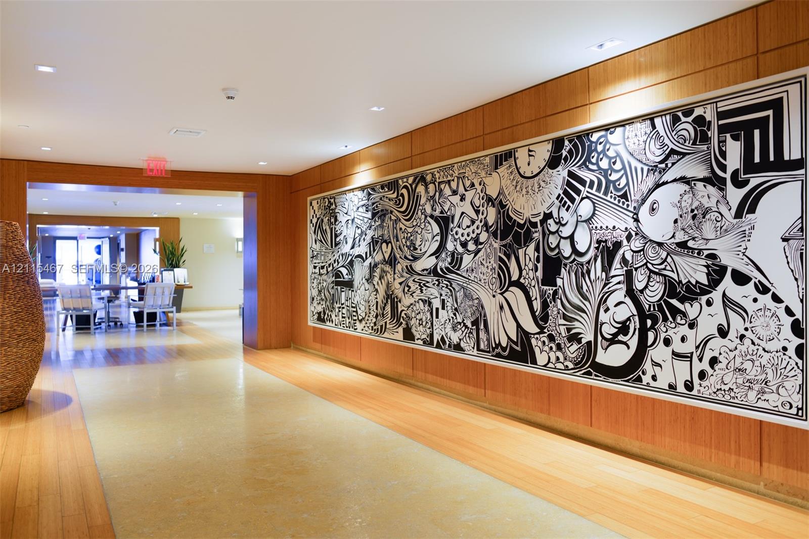 Interior corridor featuring wood-paneled walls, recessed ceiling lighting, and polished stone flooring with wood-finish borders