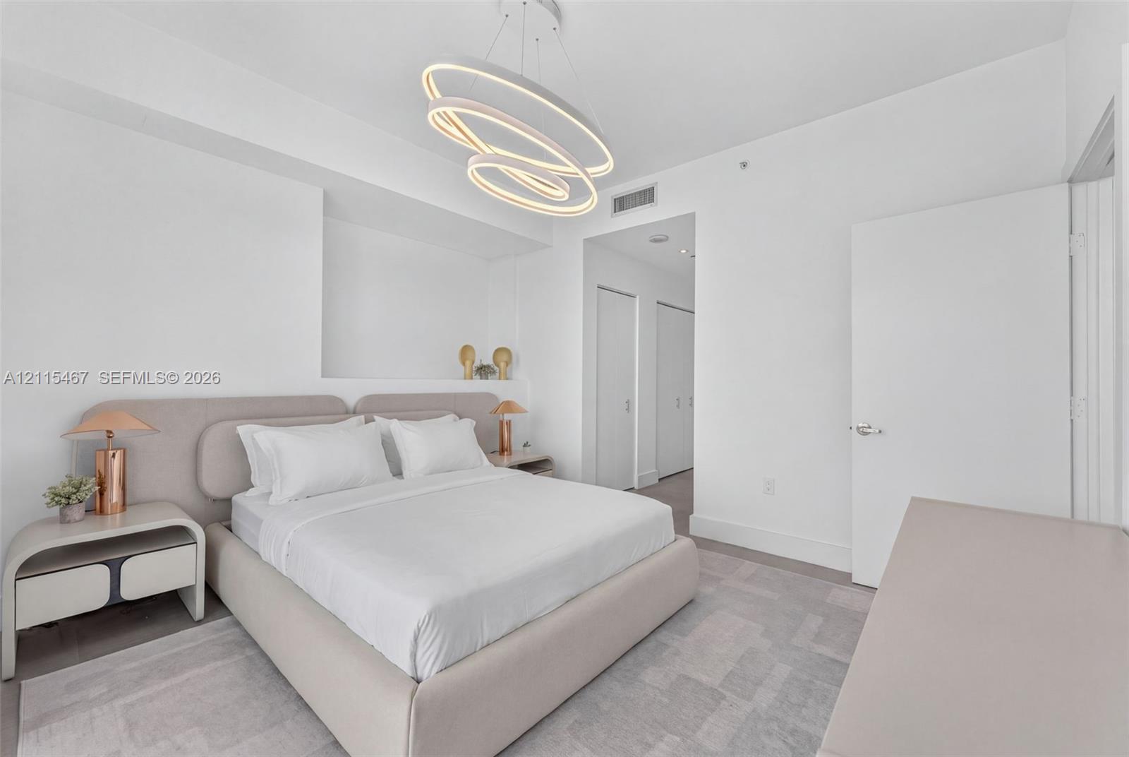 Contemporary geometric LED chandelier, neutral wall-to-wall carpeting, and recessed wall niche with integrated shelving