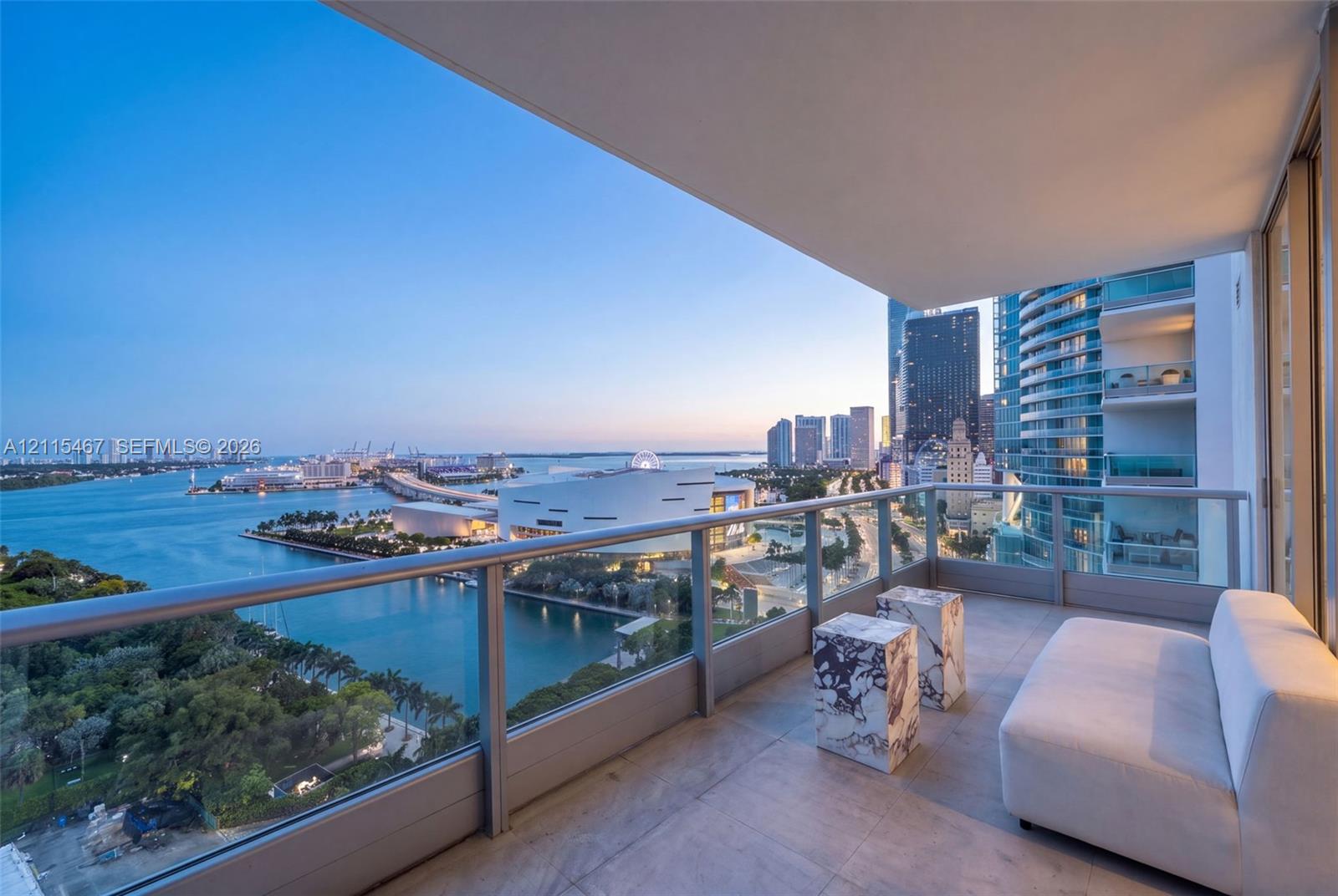 Covered private balcony featuring large-format stone floor tiles and a minimalist glass-panel railing