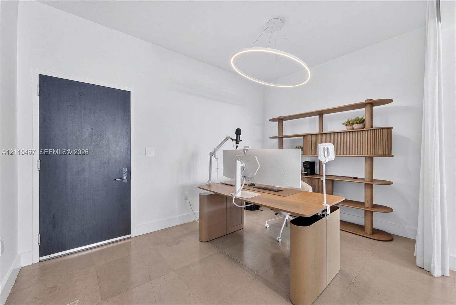 Minimalist room featuring large-format tile flooring, a modern circular LED pendant light, and a solid dark-finish entry door