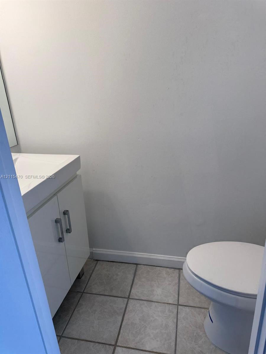 White vanity with a rectangular sink, polished metal hardware, and tiled flooring