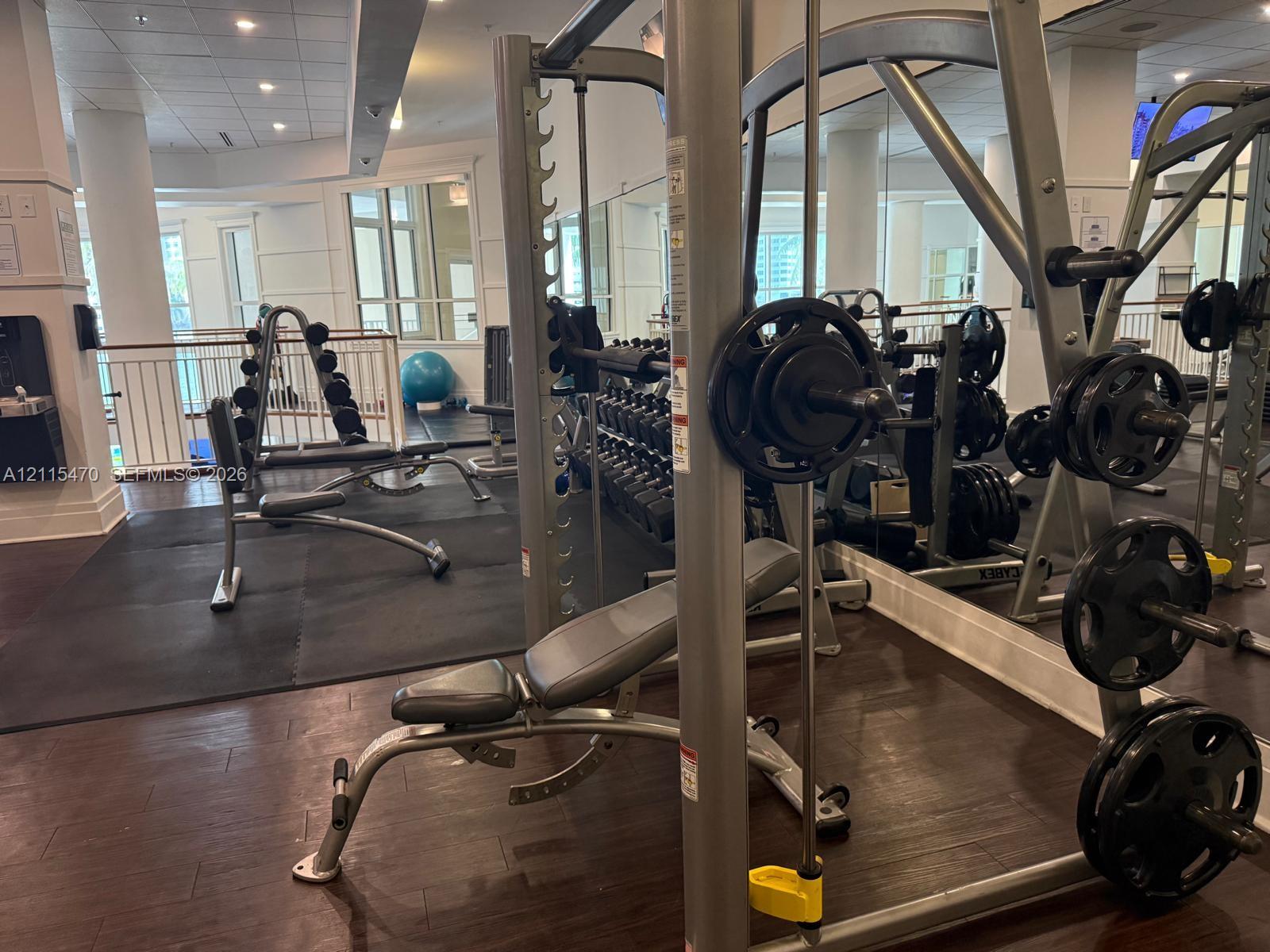 Fitness center featuring large mirrors, wood-finish flooring, and recessed ceiling lighting