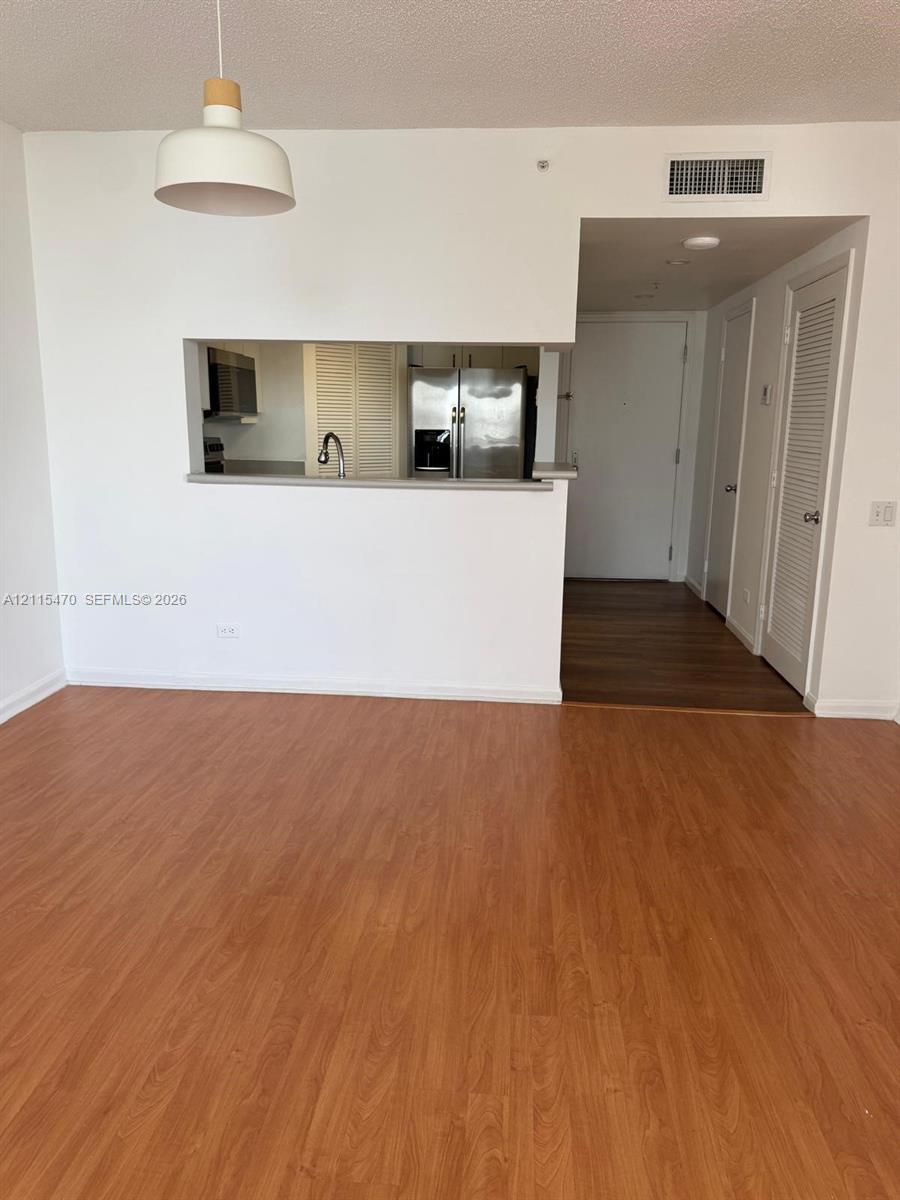Interior featuring wood-finish flooring, a kitchen pass-through, stainless steel appliances, and a dome-style pendant light fixture