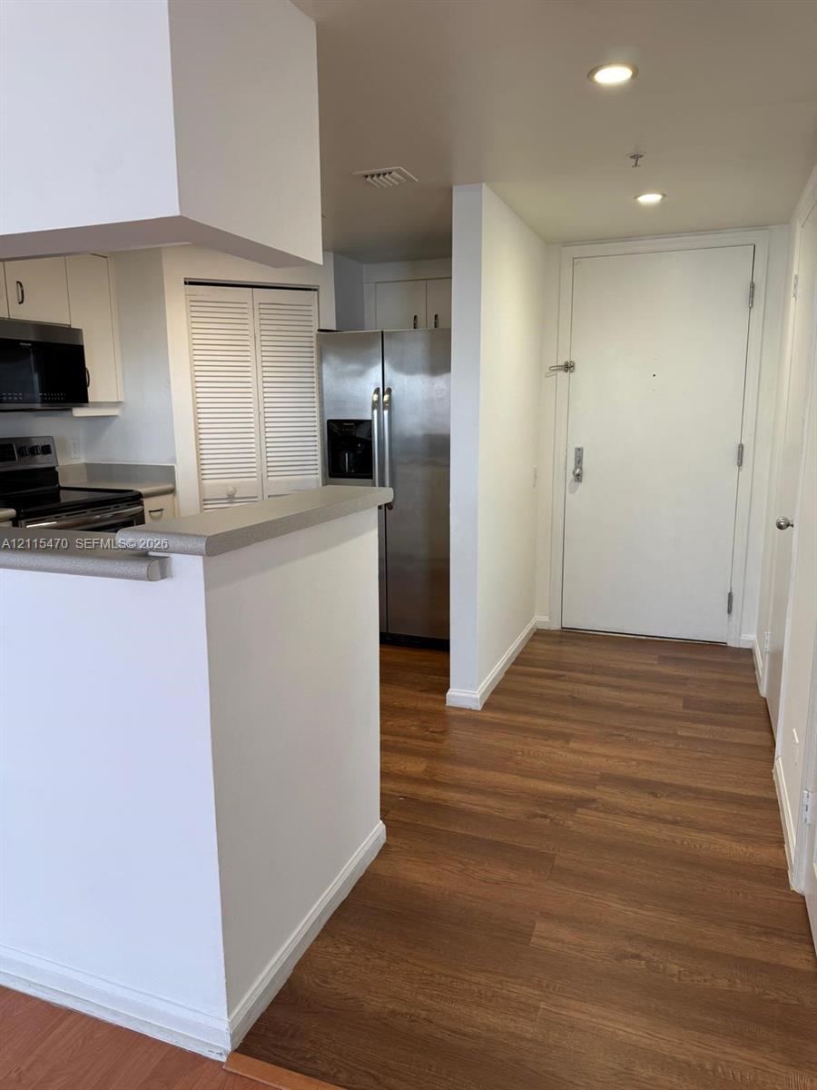 Kitchen featuring stainless steel appliances, wood-finish flooring, recessed lighting, and a breakfast bar with stone-surface countertop