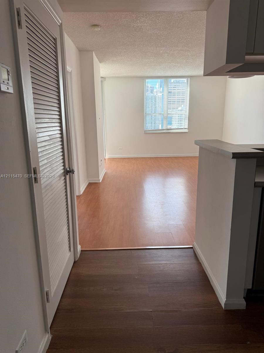 Wood-finish flooring throughout, louvered closet door, and large window with urban exposure