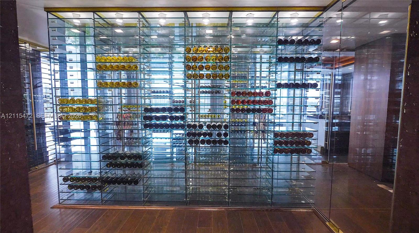 Temperature-controlled wine display featuring floor-to-ceiling glass paneling, metal racking, integrated recessed lighting, and wood-finish flooring