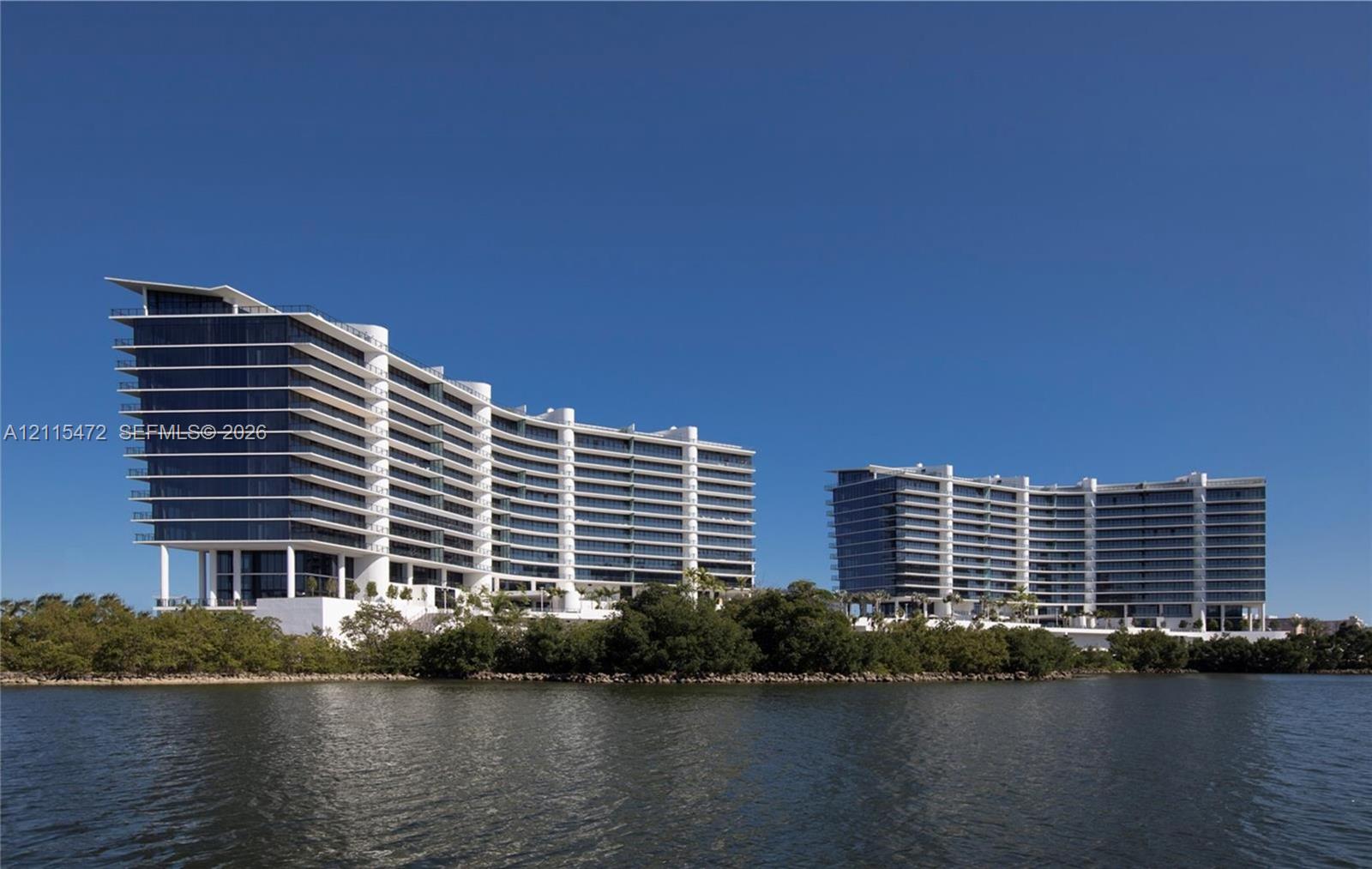Curved architectural high-rise structures featuring expansive floor-to-ceiling windows, private balconies, and waterfront positioning