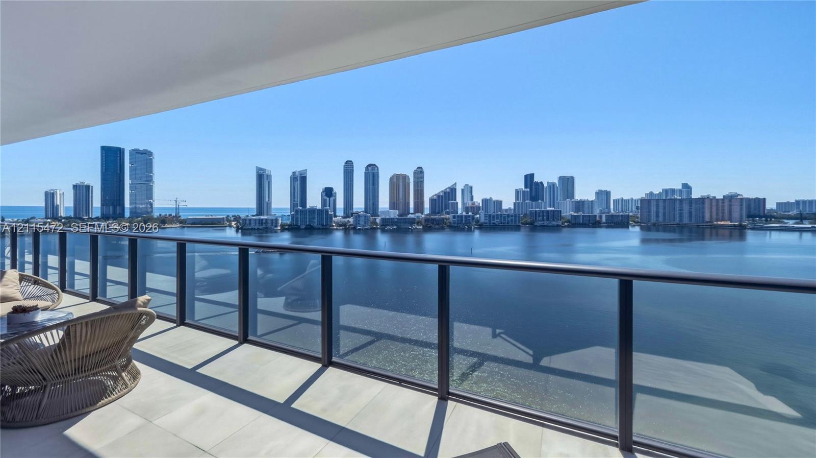 Covered terrace featuring light-toned tile flooring and a glass-paneled railing with a metal frame