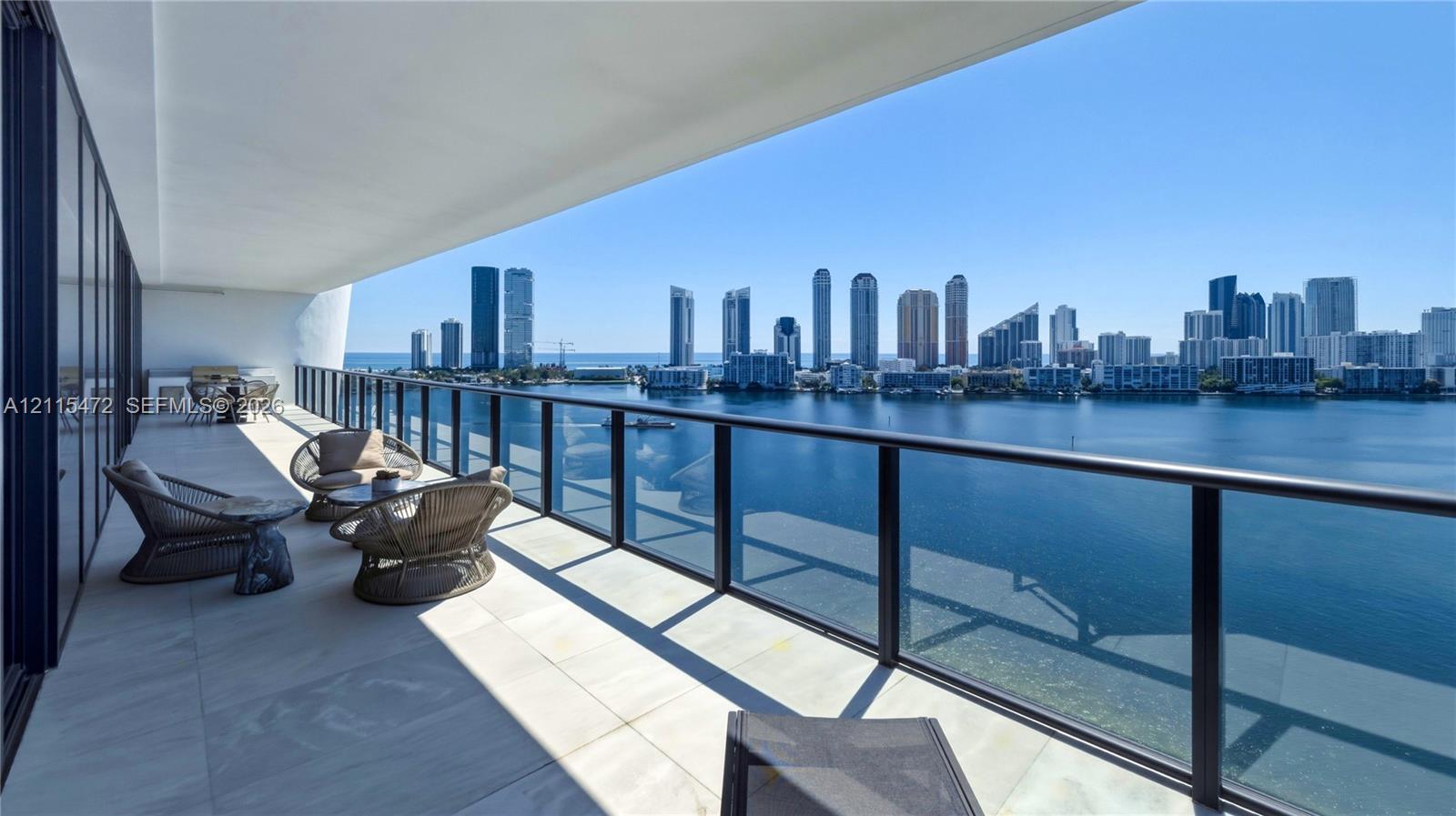 Expansive covered balcony featuring large-format stone flooring and a glass panel railing