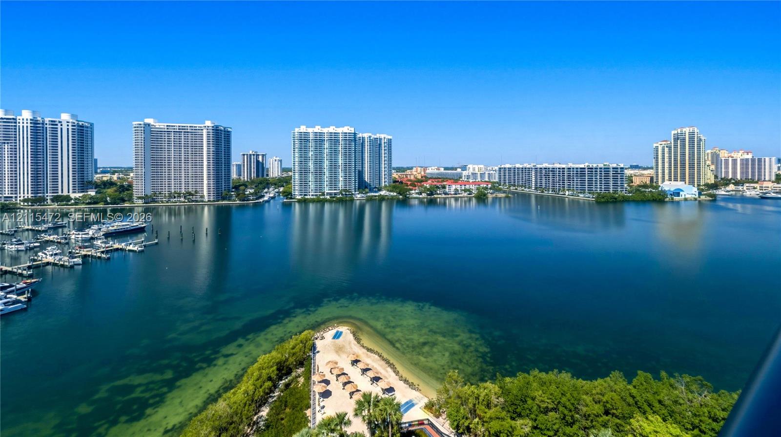 Panoramic waterfront perspective featuring a protected harbor, private boat slips, a coastal sand peninsula, and dense native vegetation