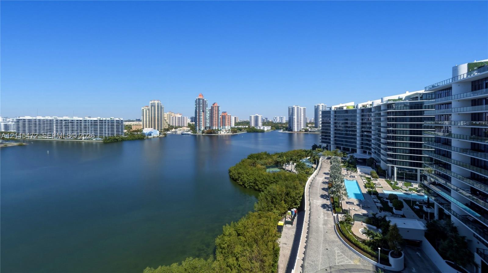 Panoramic waterfront perspective featuring an expansive bay, surrounding high-rise structures, and established landscaping