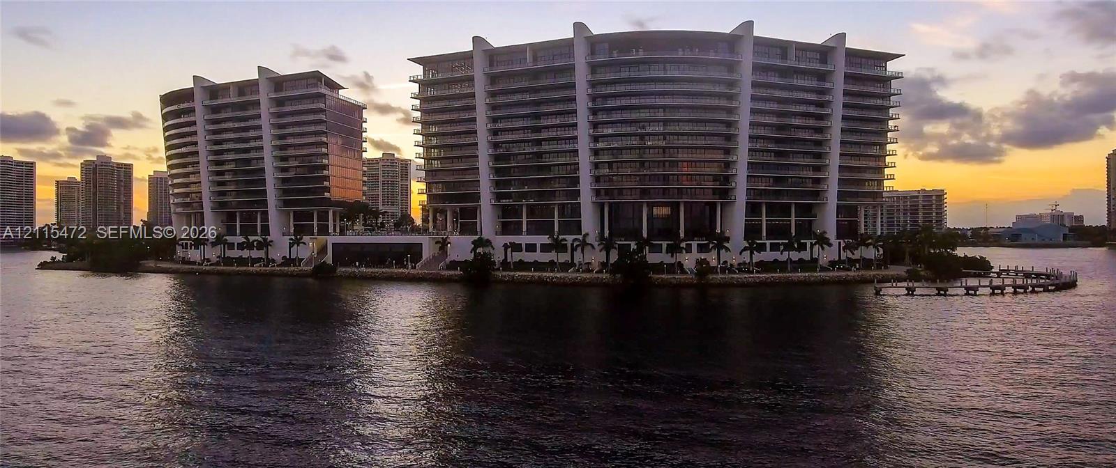 Waterfront high-rise complex featuring curvilinear architecture, tiered balconies, floor-to-ceiling glass paneling, and private maritime dockage