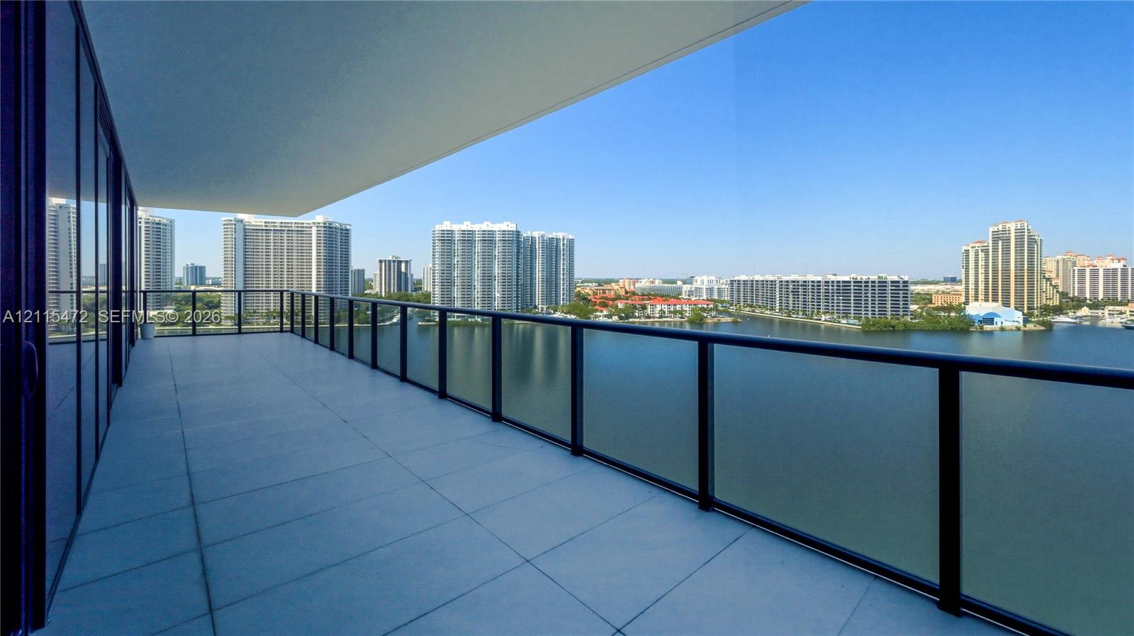 Expansive covered balcony featuring large-format tile flooring and a glass panel railing