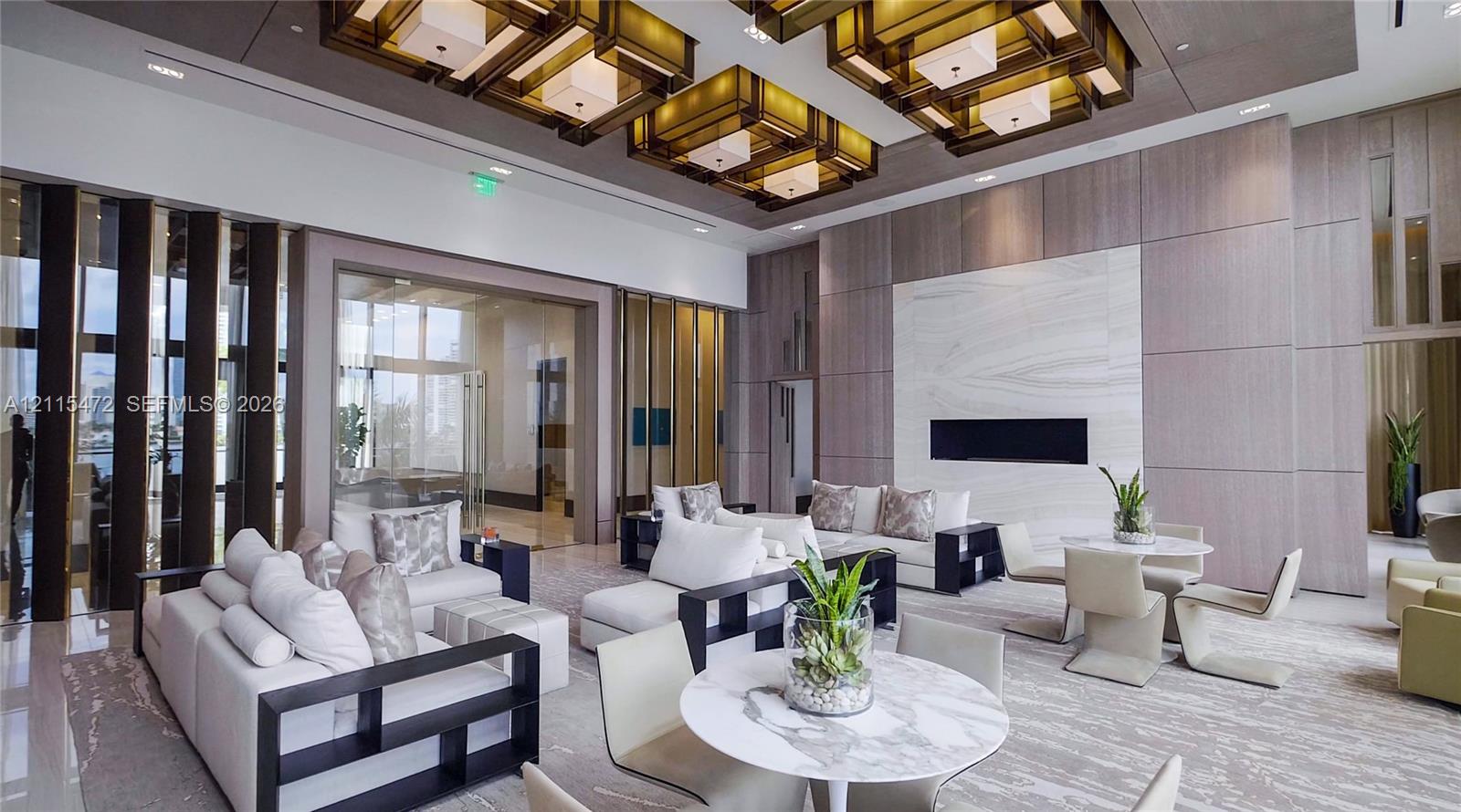 High-ceilinged common area featuring architectural recessed lighting, a stone-surround linear fireplace, floor-to-ceiling wood-panel wall treatments, and vertical slat room dividers
