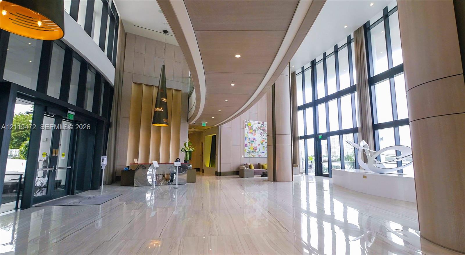 Grand foyer featuring floor-to-ceiling windows, polished stone flooring, a curved wood-paneled ceiling feature, and integrated recessed lighting