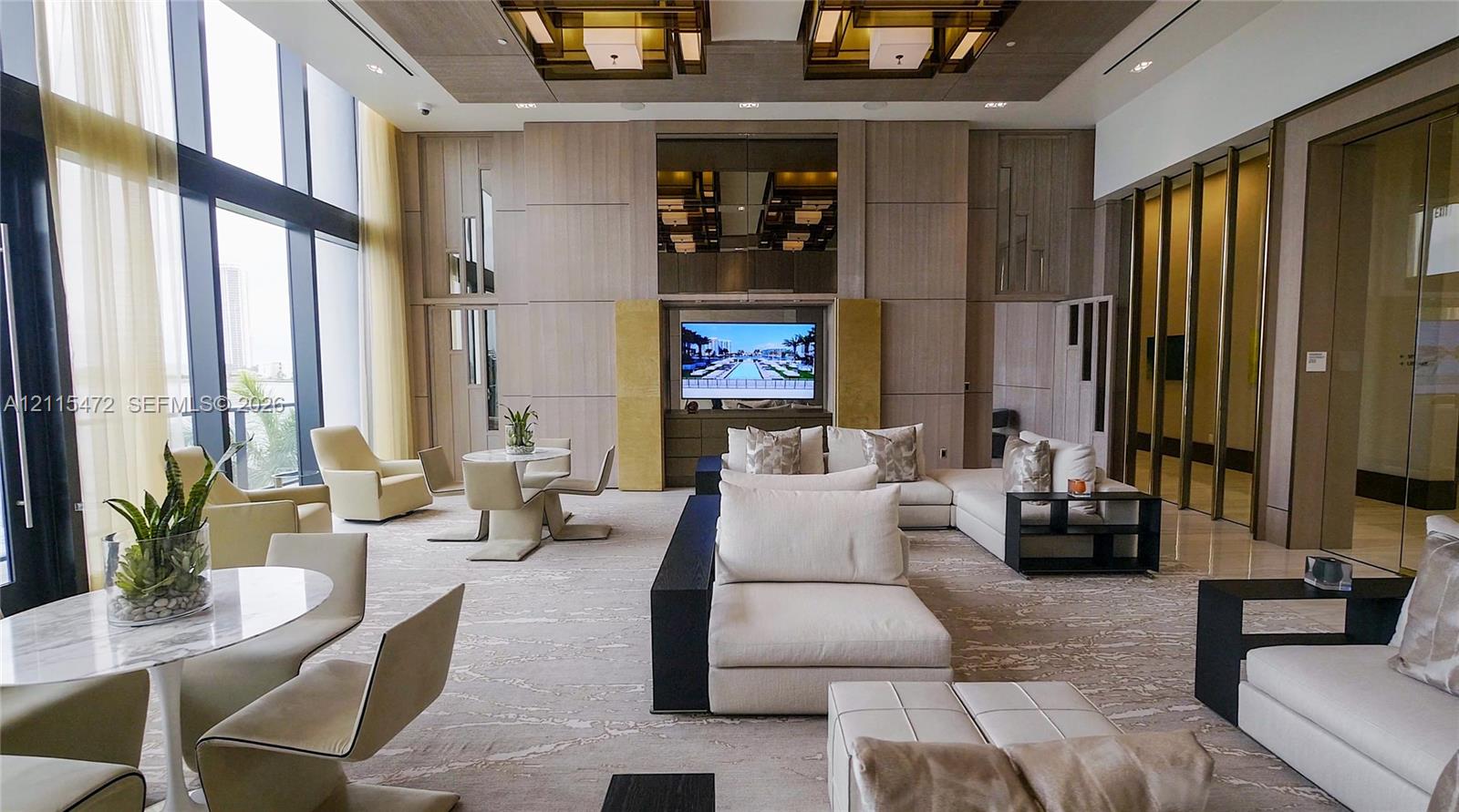 Floor-to-ceiling windows, wood-paneled wall treatments, recessed ceiling lighting with geometric fixtures, and integrated built-in media center