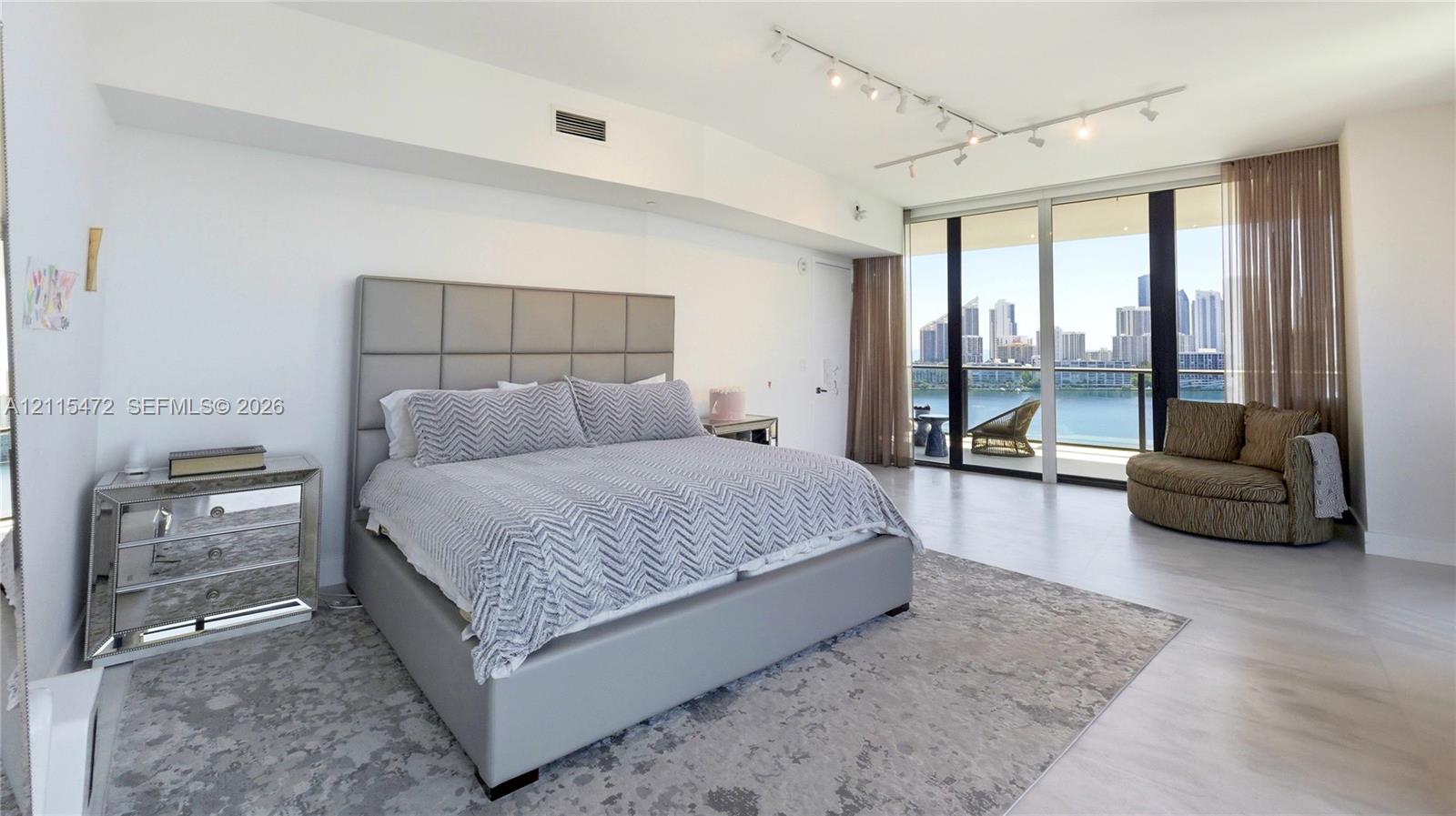 Floor-to-ceiling windows, wood-finish flooring, adjustable track lighting, and a private balcony