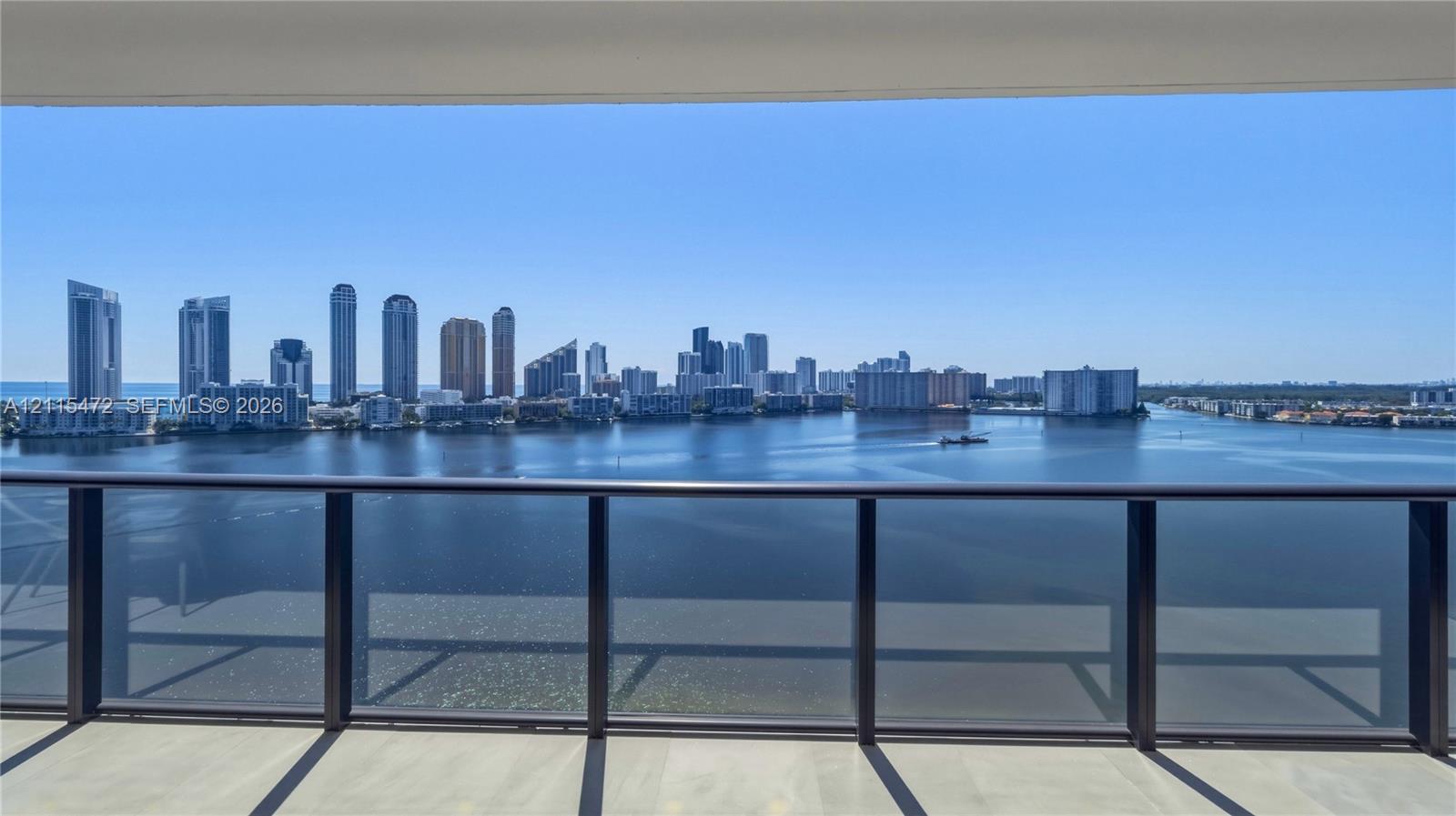 Covered balcony featuring sleek dark metal railings and tile flooring, showcasing water and cityscape scenery