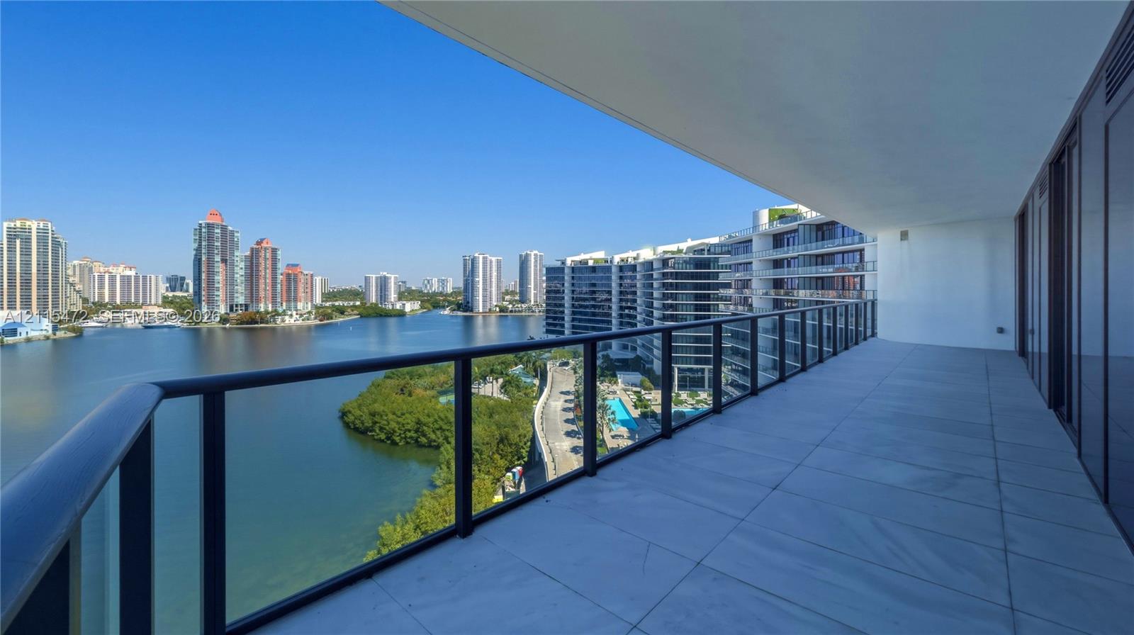 Covered balcony with large-format stone flooring and a black metal railing overlooking the waterway and cityscape