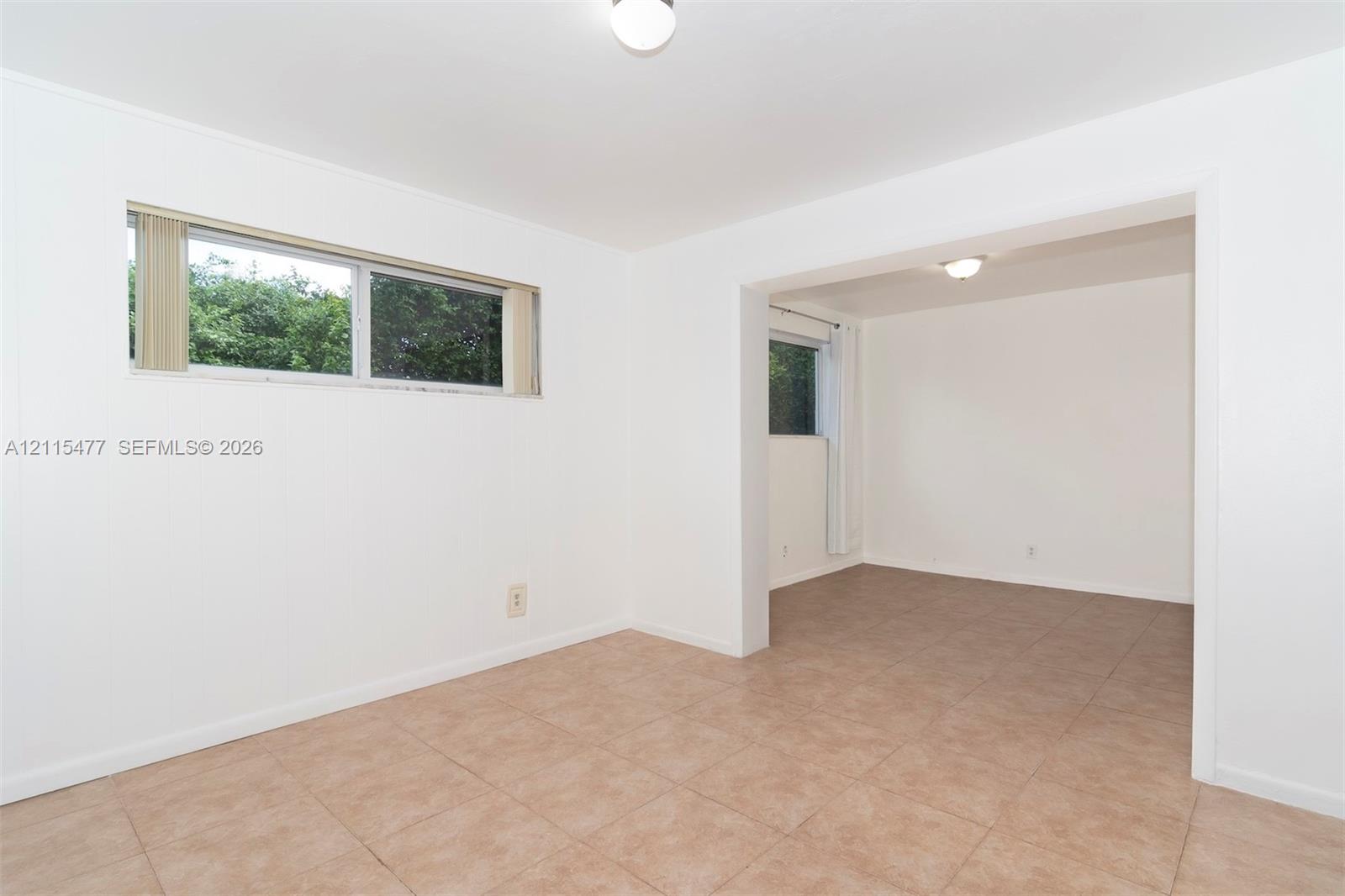 Interior space featuring neutral wall tones, large-format tile flooring, and horizontally oriented windows with natural light exposure