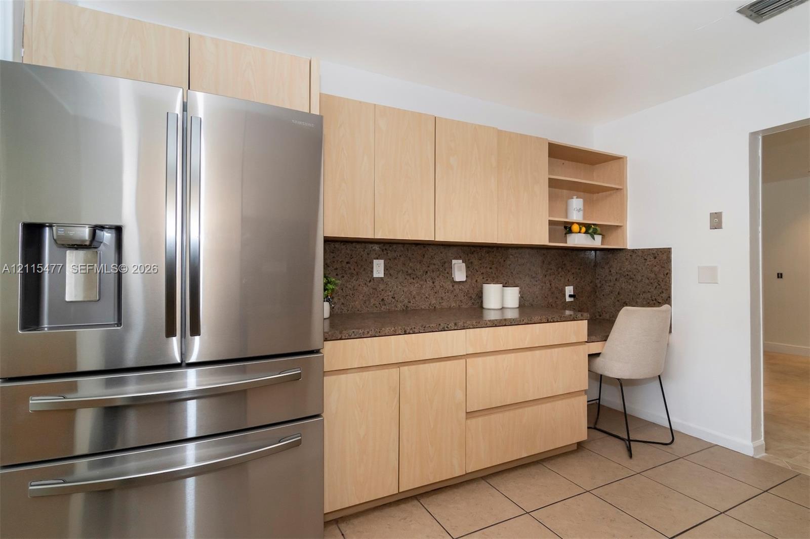 Kitchen area featuring light wood-finish cabinetry, a stainless steel refrigerator, stone-finish countertops, tile flooring, and integrated open shelving