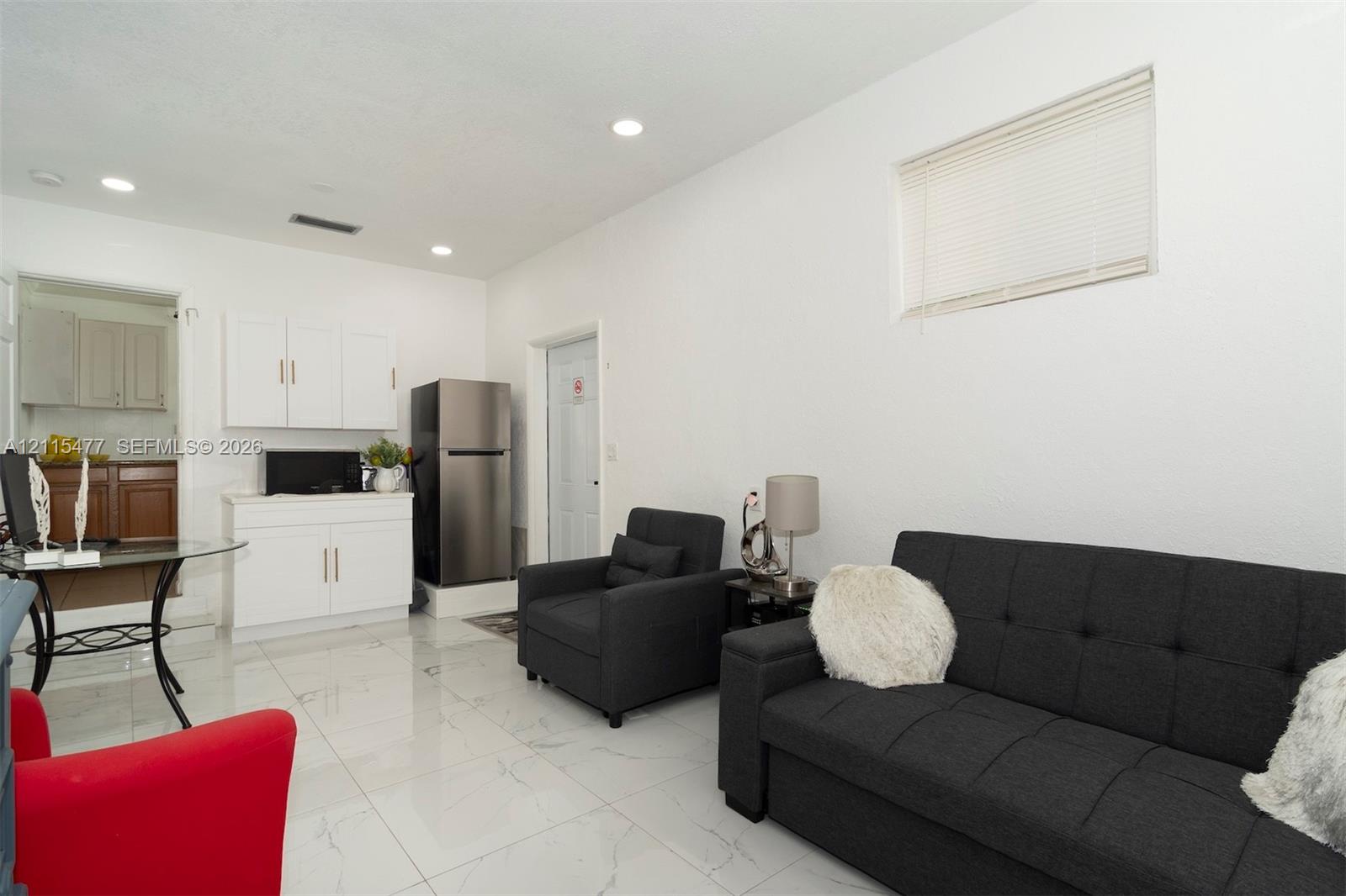 Open living space featuring light-colored tile flooring, recessed lighting, white cabinetry, and a horizontal window