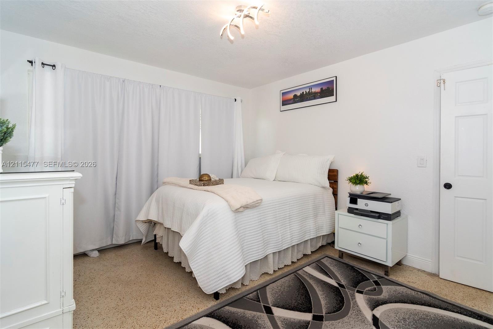 Neutral-toned carpeting, ceiling-mounted decorative light fixture, and six-panel interior door