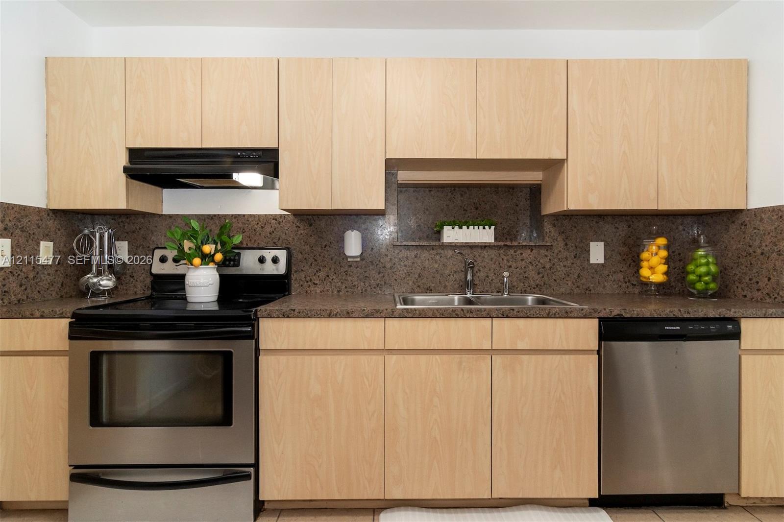 Kitchen featuring light-finish cabinetry, solid surface countertops, a speckled stone backsplash, stainless steel dishwasher, and a stainless steel freestanding range