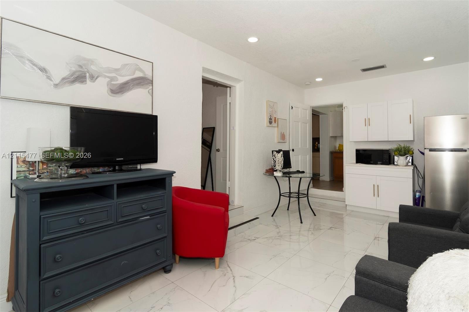 Polished tile flooring, recessed ceiling lighting, and white built-in cabinetry featuring metallic hardware